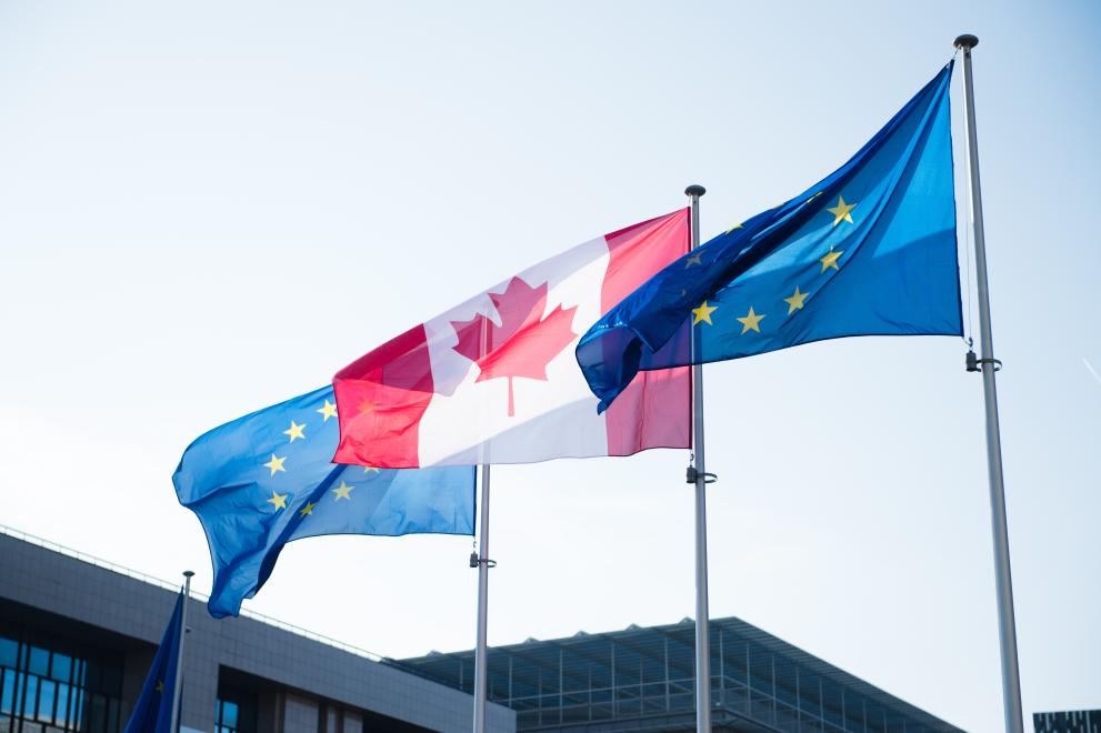 Pictures of EU and Canadian flags in front of the Berlaymont building