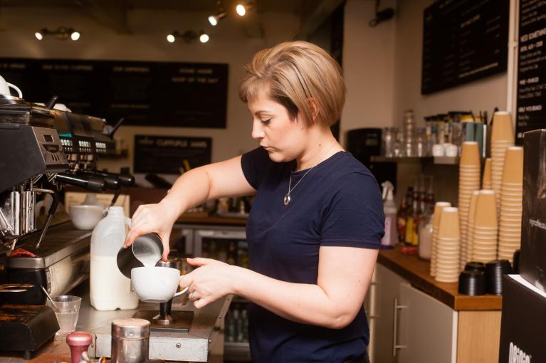 Une femme barista prépare un café derrière un comptoir