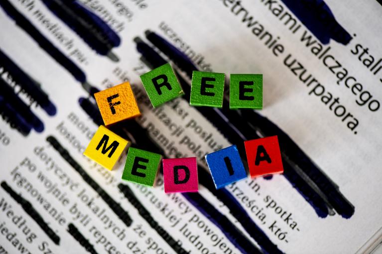 Des blocs de bois épellent les mots 'free media' ('médias libres') sur fond de papier à journal